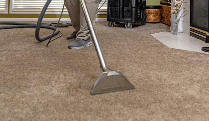 worker cleaning carpet with equipment