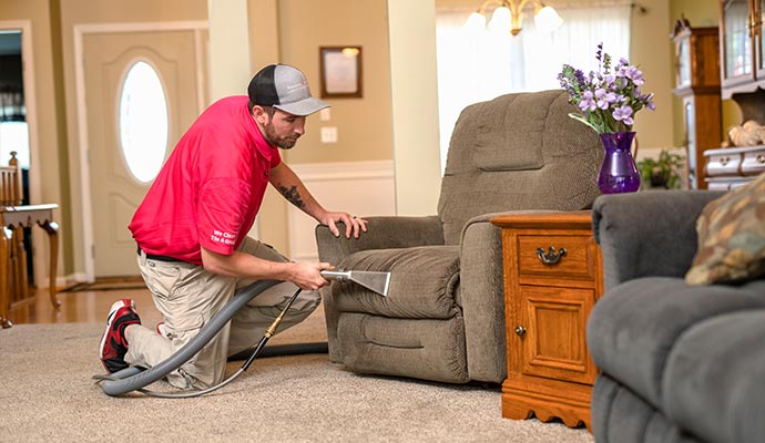 Person cleaning upholstery with vacuum cleaner