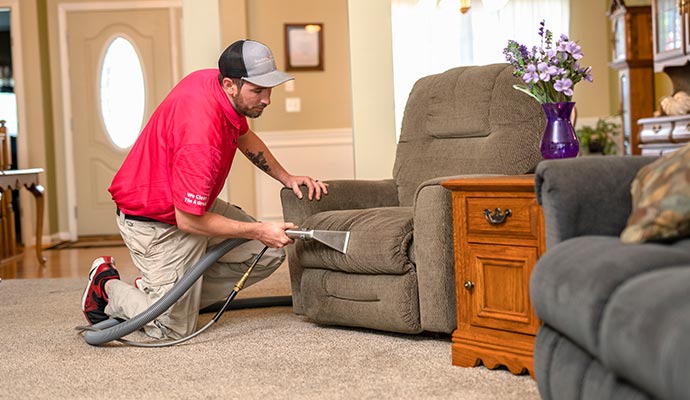 Person cleaning a couch with a vacuum cleaner